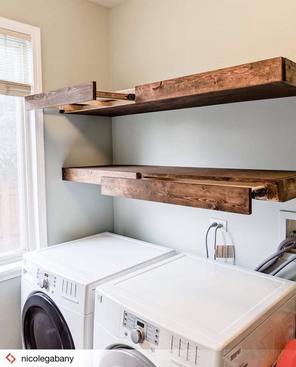 10 Small Laundry Closet Ideas That Actually Fit in a Hallway 5 Two thick dark wood floating shelves mounted on a light blue wall above white laundry machines.