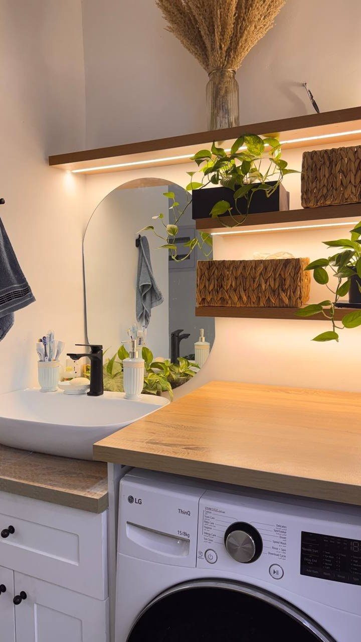 10 Small Laundry Closet Ideas That Actually Fit in a Hallway 2 Laundry room with wooden floating shelves featuring integrated LED strip lighting and decorative plants.