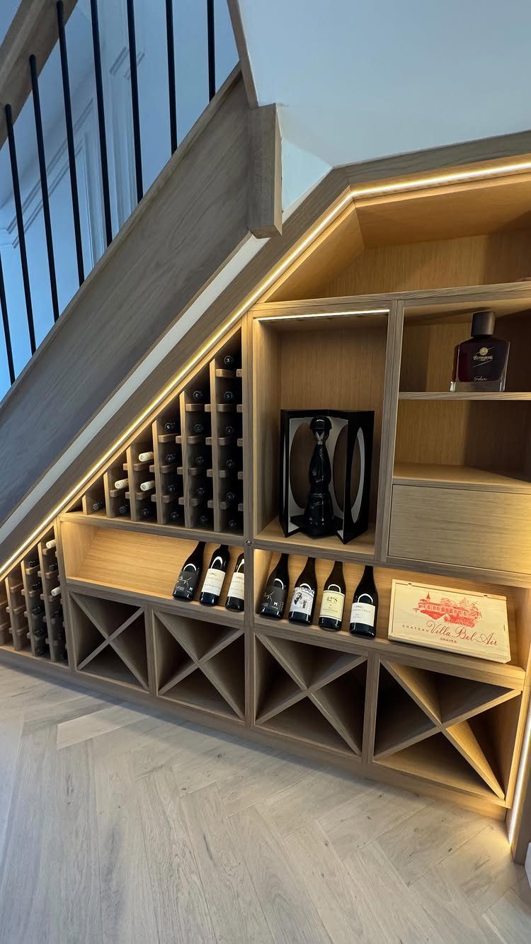 7 Stairs with Under Storage Ideas That Actually Work 6 Wooden built-in wine rack storage with integrated LED lighting located underneath a staircase.