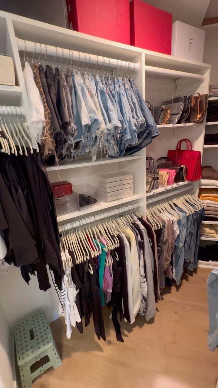 8 Storage Closet Organization Ideas for Tighter Spaces 2026 8 White closet shelving unit filled with organized clothing, denim shorts, handbags, and red storage boxes.