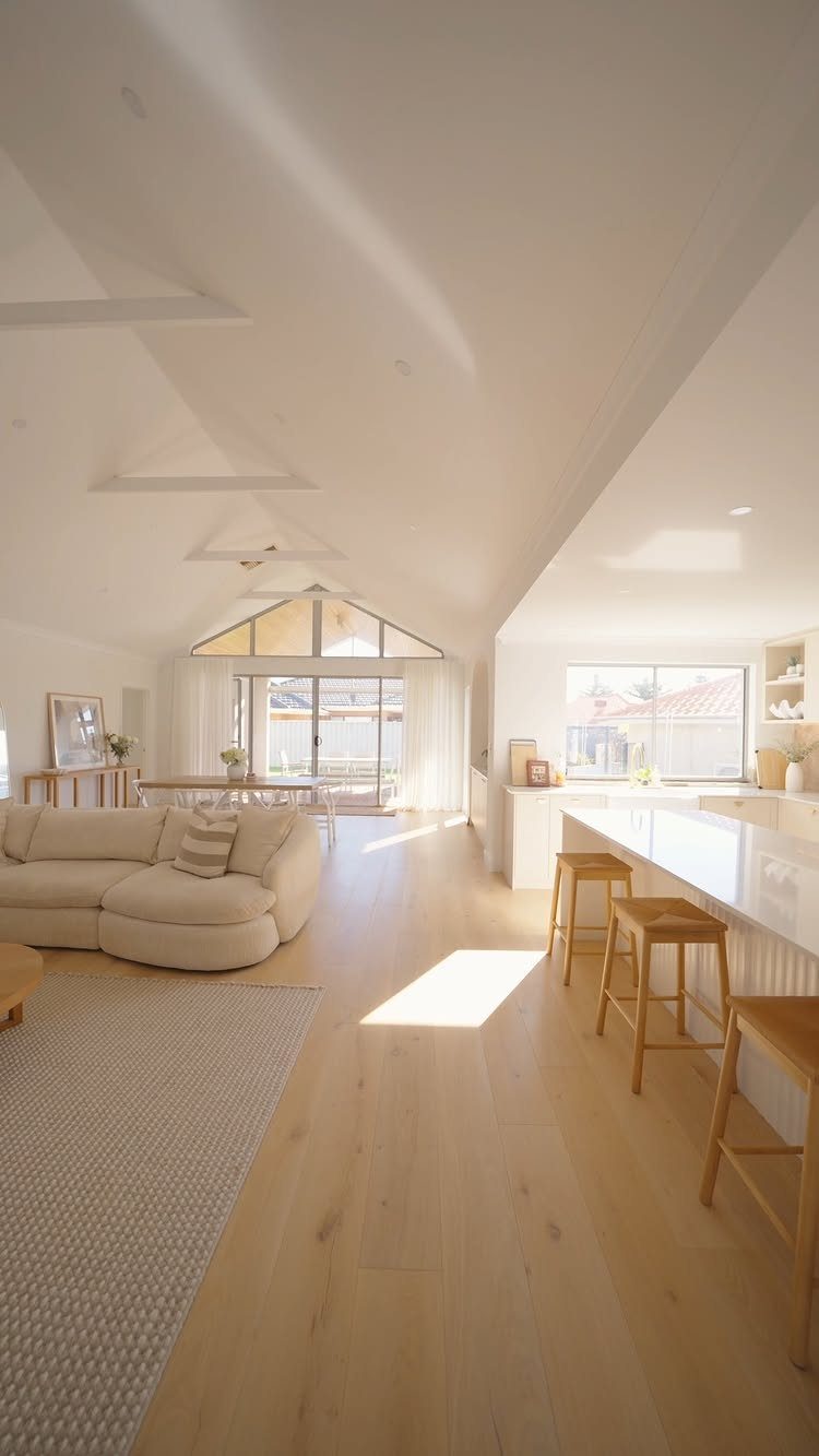 Light colored wood floors running through a bright, modern open-plan living and kitchen space.