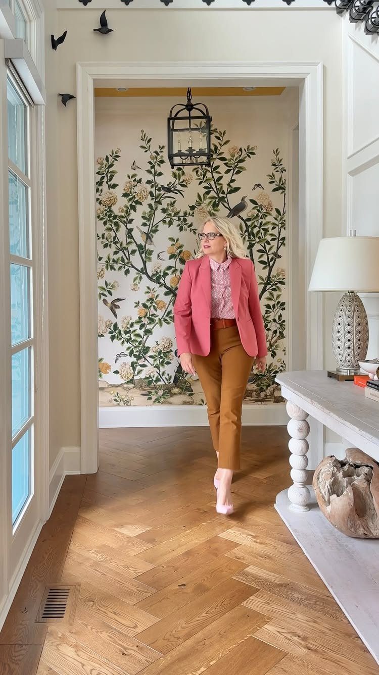 Woman walking across a light brown herringbone patterned wood floor in a bright room.
