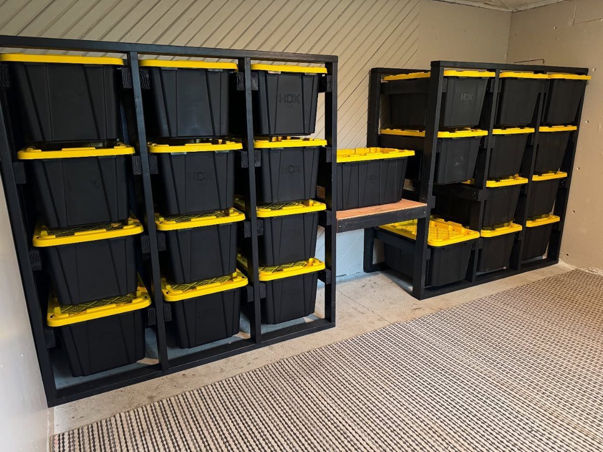 Black metal shelves filled with black and yellow plastic storage bins in a basement.