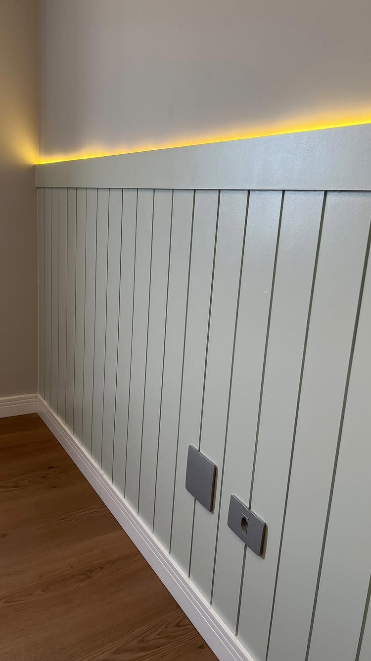 Light grey vertical shiplap wainscoting installed on a wall with warm LED backlighting.