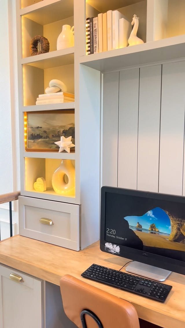 Light grey built-in desk unit with vertical shiplap paneling and illuminated shelving units.