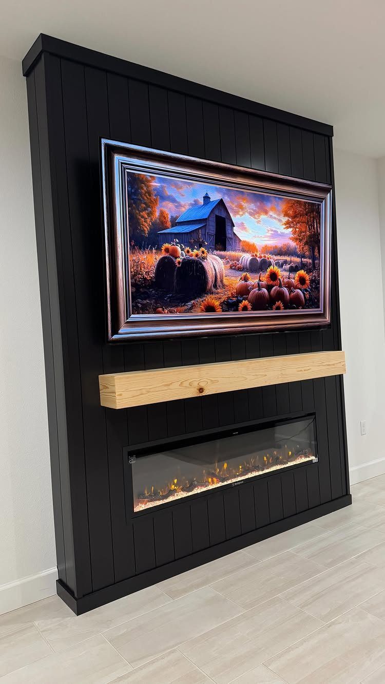 Black vertical shiplap wall with a wooden mantel and an electric fireplace below a framed painting.