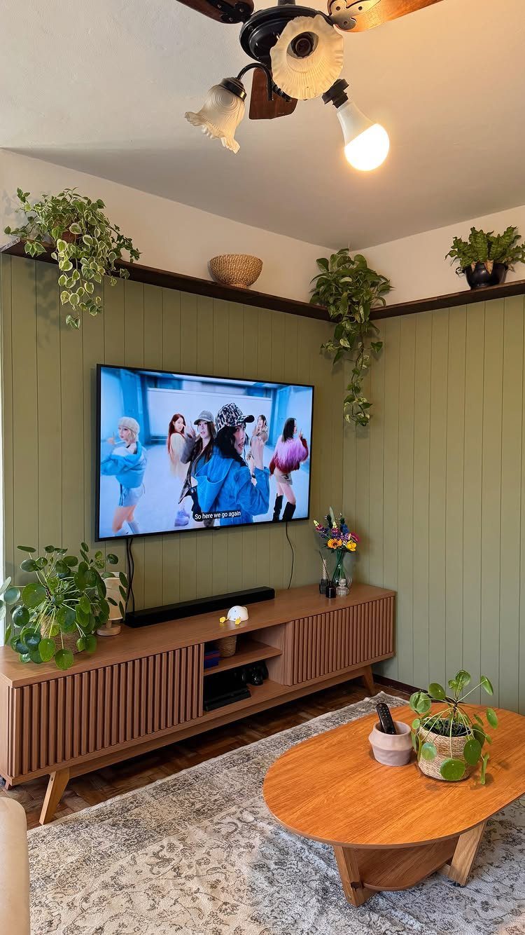 Sage green vertical shiplap wall in a living room with a television and wooden furniture.