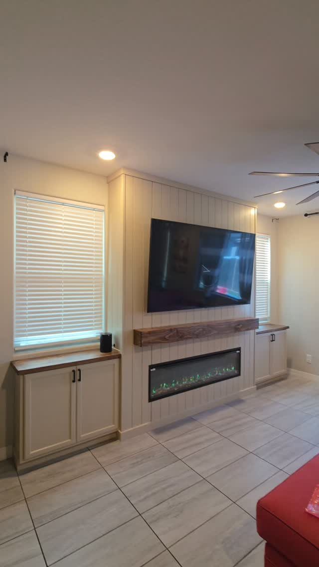 Vertical white shiplap accent wall with a mounted television and an electric fireplace below.