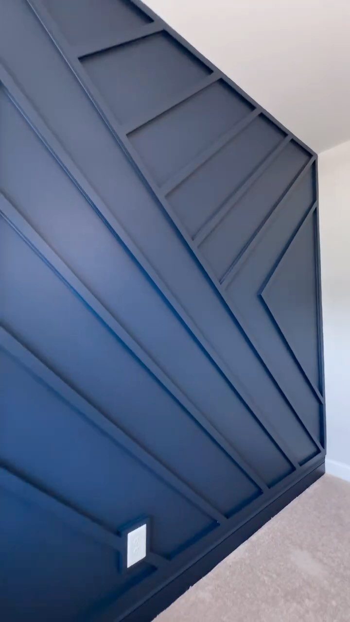 Navy blue wall with a geometric pattern of raised wooden slats in a room.