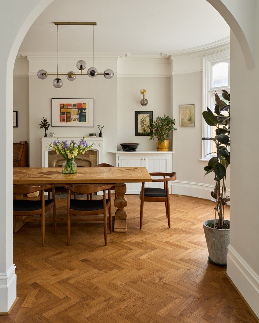 Herringbone pattern wood flooring in a bright, modern dining room with wooden furniture.