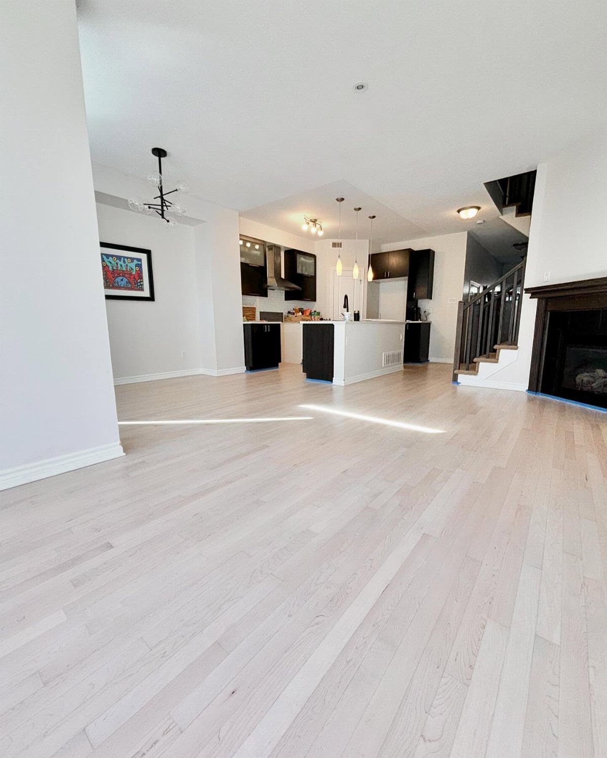Whitewashed wood plank flooring in a bright, open-concept living space and kitchen area.