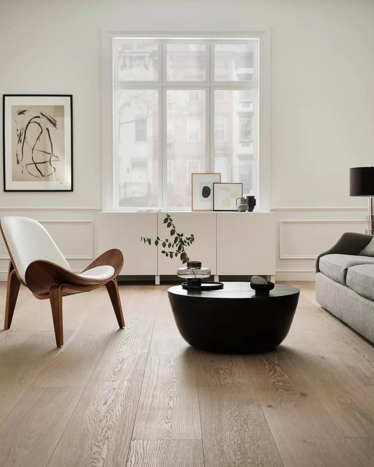 Wide light wood planks cover the floor of a modern, minimalist living room.