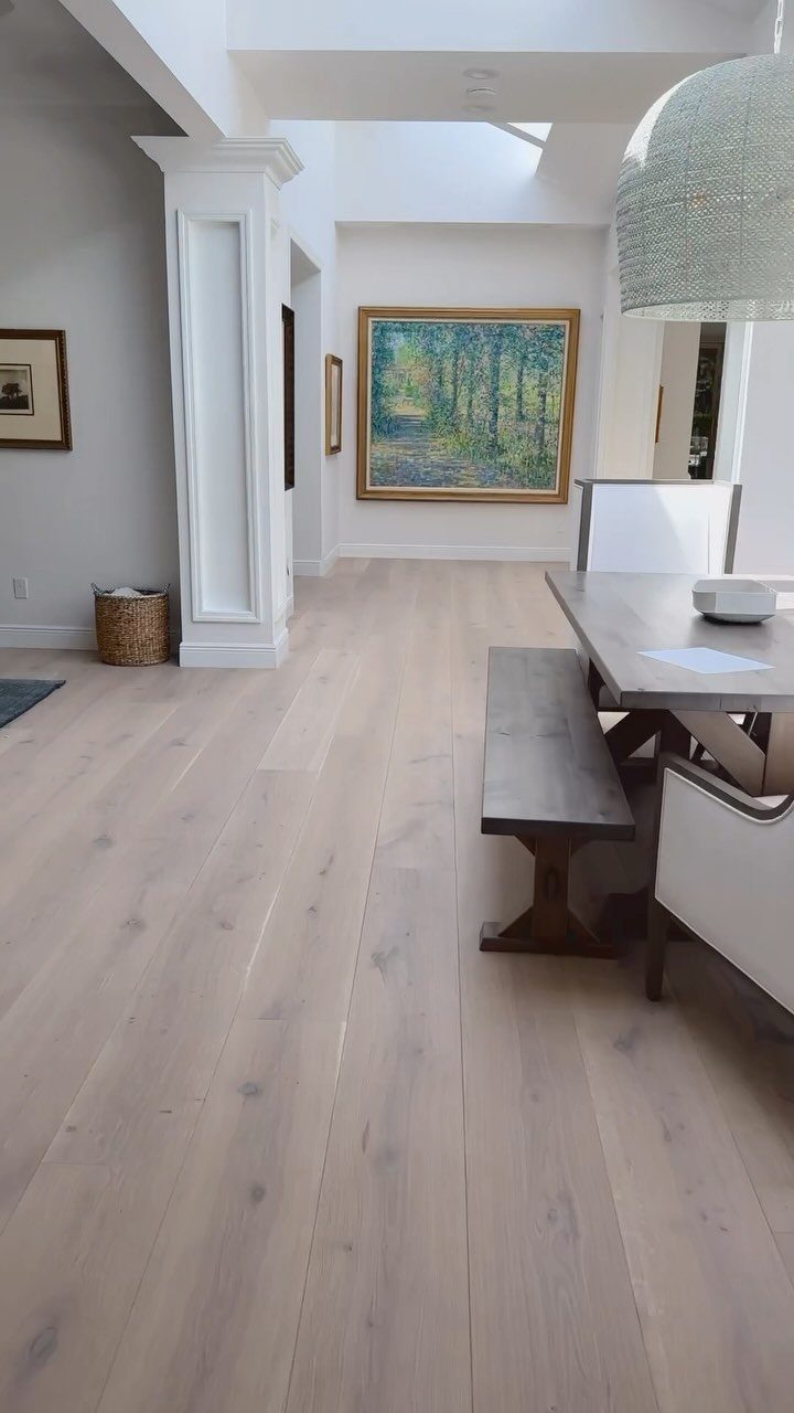 Wide light-colored wood planks covering the floor of a bright, modern dining room.