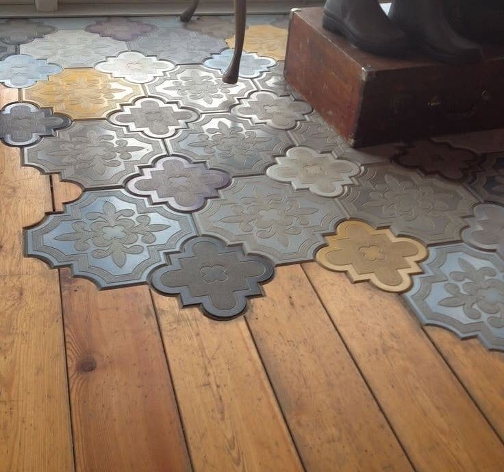 Decorative patterned tiles seamlessly transitioning into wide light brown wood planks on a floor.